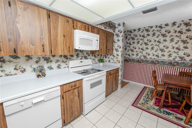 3315 Cross Fox Dr, Mulberry, FL 33860 - kitchen with white appliances, wallpapered walls, light countertops, brown cabinets, and light tile patterned flooring