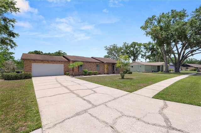 3315 Cross Fox Dr, Mulberry, FL 33860 - ranch-style house featuring a front yard, a garage, driveway, and brick siding