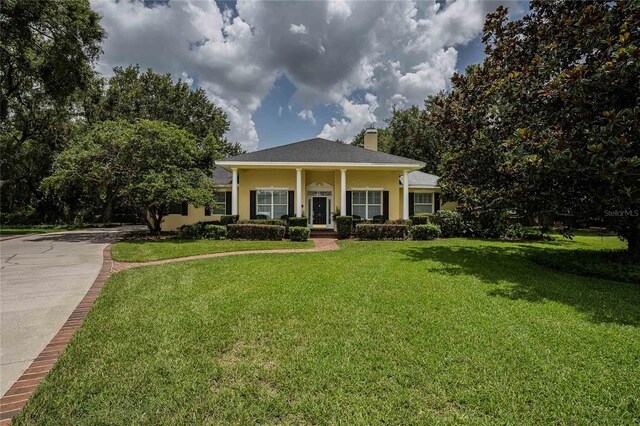 1589 Royal Forest Ct, Lakeland, FL 33811 - view of front facade with a chimney, a front yard, concrete driveway, and stucco siding