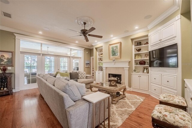 1589 Royal Forest Ct, Lakeland, FL 33811 - living area with ornamental molding, a ceiling fan, light wood finished floors, a glass covered fireplace, and built in shelves