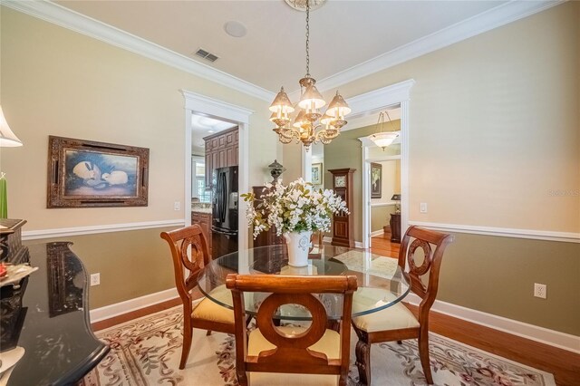 1589 Royal Forest Ct, Lakeland, FL 33811 - dining area with light wood-type flooring, a chandelier, and crown molding