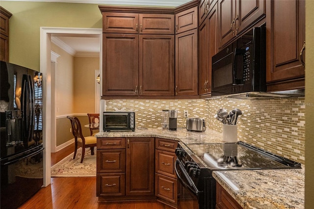 1589 Royal Forest Ct, Lakeland, FL 33811 - kitchen with black appliances, crown molding, tasteful backsplash, dark wood-style flooring, and light stone countertops