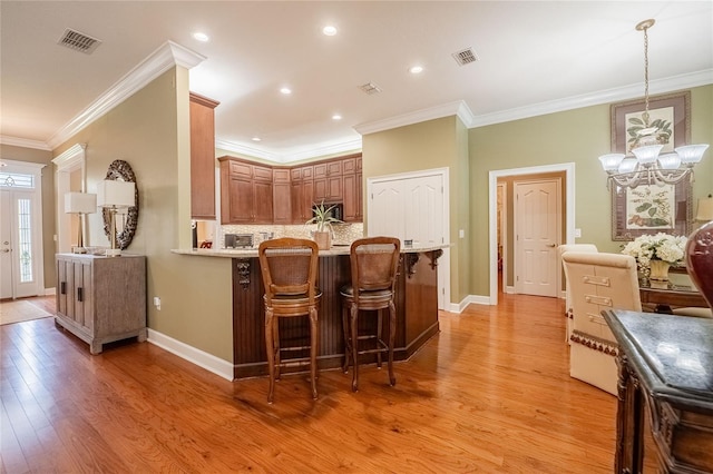 1589 Royal Forest Ct, Lakeland, FL 33811 - kitchen featuring light wood-style flooring, a breakfast bar, crown molding, tasteful backsplash, and stainless steel microwave