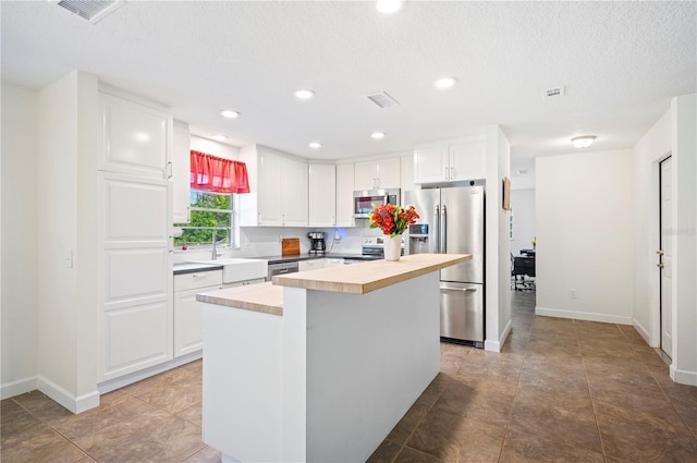 6507 Shadowbrook Run, Lakeland, FL 33813 - kitchen with stainless steel appliances, light countertops, white cabinets, a kitchen island, and a textured ceiling