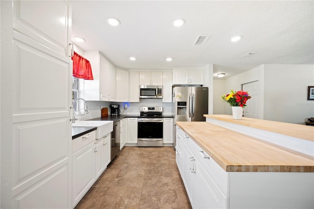 6507 Shadowbrook Run, Lakeland, FL 33813 - kitchen with stainless steel appliances, wooden counters, white cabinetry, recessed lighting, and a center island