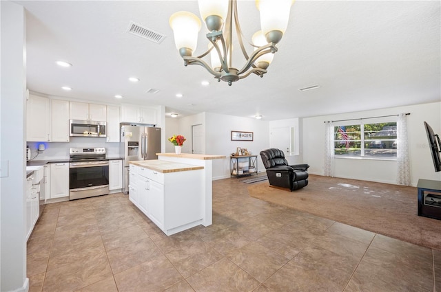 6507 Shadowbrook Run, Lakeland, FL 33813 - kitchen with stainless steel appliances, a chandelier, white cabinets, a kitchen island, and recessed lighting