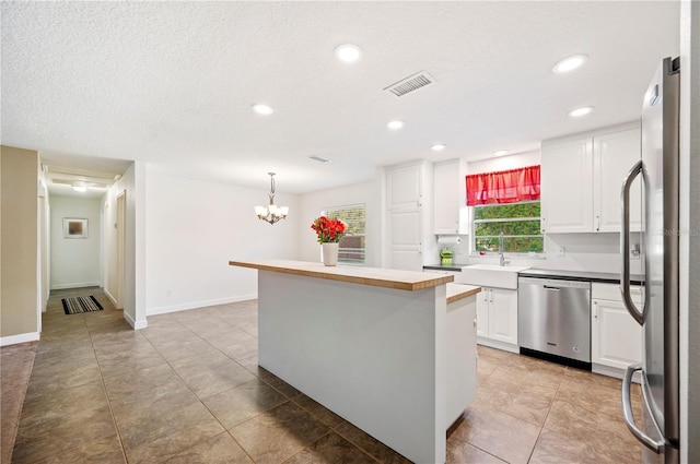 6507 Shadowbrook Run, Lakeland, FL 33813 - kitchen with stainless steel appliances, white cabinets, a kitchen island, recessed lighting, and a chandelier