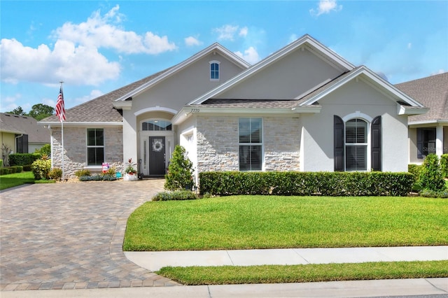 7770 Lake James Blvd, Lakeland, FL 33810 - single story home featuring stone siding, a front yard, stucco siding, driveway, and an attached garage