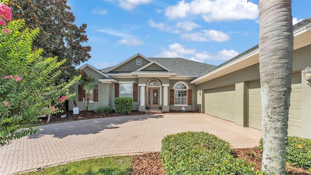 2817 High Winds Ln, Lakeland, FL 33813 - view of front of property featuring decorative driveway, an attached garage, stucco siding, and a shingled roof