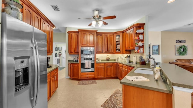 2817 High Winds Ln, Lakeland, FL 33813 - kitchen featuring stainless steel appliances, ceiling fan, a peninsula, brown cabinets, and glass insert cabinets