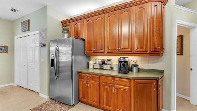 2817 High Winds Ln, Lakeland, FL 33813 - kitchen with stainless steel fridge, brown cabinetry, and decorative backsplash
