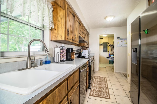 6920 Newman Cir E, Lakeland, FL 33811 - kitchen with appliances with stainless steel finishes, brown cabinetry, under cabinet range hood, light tile patterned floors, and light countertops