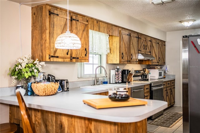 6920 Newman Cir E, Lakeland, FL 33811 - kitchen featuring appliances with stainless steel finishes, brown cabinetry, light countertops, under cabinet range hood, and a textured ceiling