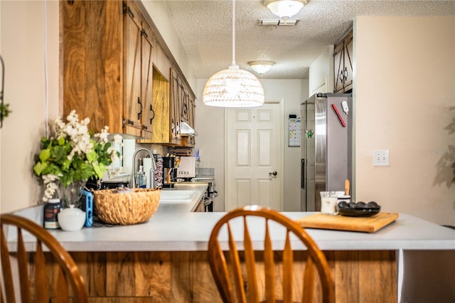 6920 Newman Cir E, Lakeland, FL 33811 - kitchen with freestanding refrigerator, brown cabinets, light countertops, a textured ceiling, and under cabinet range hood