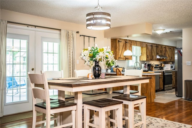 6920 Newman Cir E, Lakeland, FL 33811 - dining room featuring a textured ceiling, light wood-type flooring, a chandelier, and french doors