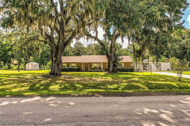 6920 Newman Cir E, Lakeland, FL 33811 - ranch-style home with a storage unit, a front yard, and view of wooded area