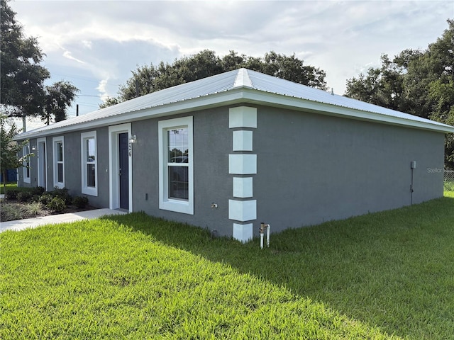 508 2nd St SW, Fort Meade, FL 33841 - view of property exterior with stucco siding, a lawn, and a metal roof