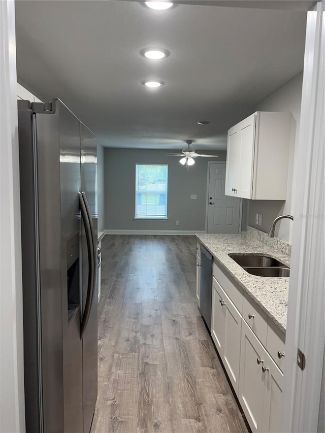 508 2nd St SW, Fort Meade, FL 33841 - kitchen with stainless steel appliances, wood finished floors, a ceiling fan, white cabinetry, and light stone counters
