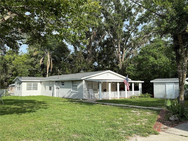 4818 Huron St, Zephyrhills, FL 33541 - view of front facade featuring covered porch, a front yard, a storage unit, and view of scattered trees