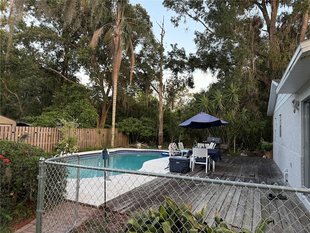 4818 Huron St, Zephyrhills, FL 33541 - view of swimming pool featuring a fenced backyard, view of wooded area, and area for grilling