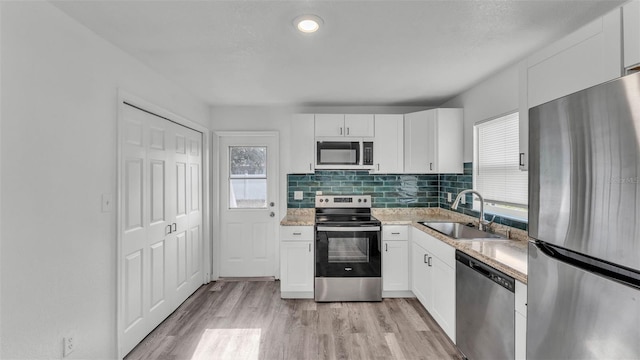 1050 Reynolds Rd, Lakeland, FL 33801 - kitchen with appliances with stainless steel finishes, light wood-type flooring, white cabinetry, tasteful backsplash, and light stone countertops