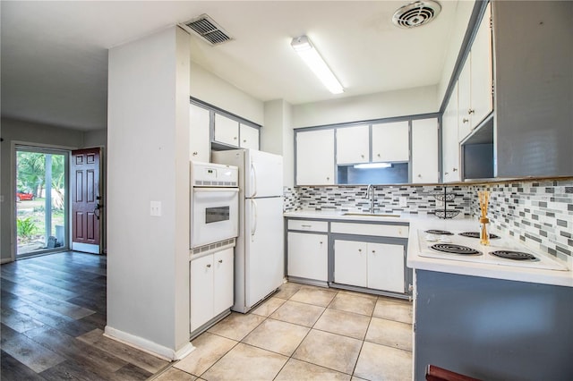 1604 Park Dr, Lakeland, FL 33803 - kitchen featuring white appliances, decorative backsplash, light countertops, white cabinetry, and light wood-style floors