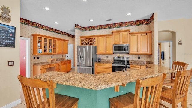 6757 High Grove Dr, Lakeland, FL 33813 - kitchen with appliances with stainless steel finishes, wallpapered walls, arched walkways, glass insert cabinets, and a kitchen breakfast bar
