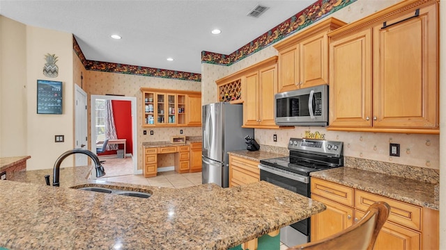6757 High Grove Dr, Lakeland, FL 33813 - kitchen featuring appliances with stainless steel finishes, wallpapered walls, light stone counters, recessed lighting, and glass insert cabinets