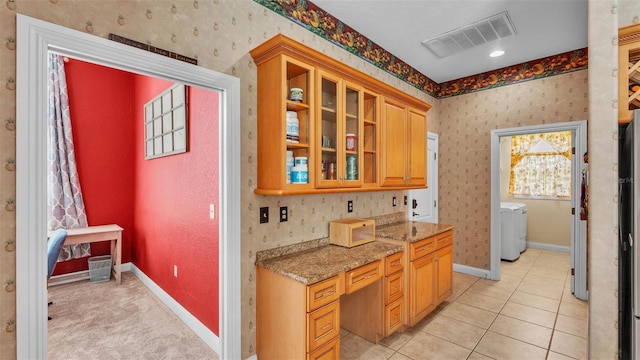 6757 High Grove Dr, Lakeland, FL 33813 - kitchen featuring washer / clothes dryer, glass insert cabinets, light stone countertops, and light tile patterned floors
