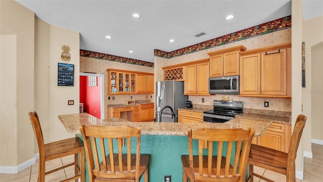 6757 High Grove Dr, Lakeland, FL 33813 - kitchen with stainless steel appliances, wallpapered walls, a kitchen breakfast bar, recessed lighting, and glass insert cabinets