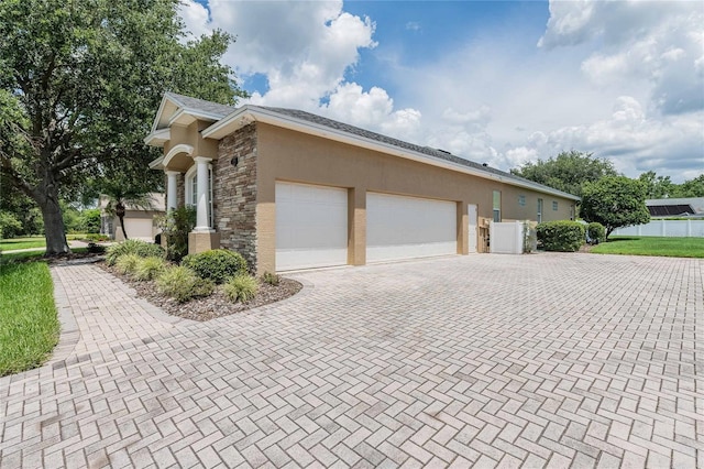 2026 Indian Sky Cir, Lakeland, FL 33813 - view of side of home featuring stone siding, decorative driveway, stucco siding, and an attached garage
