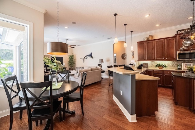 2026 Indian Sky Cir, Lakeland, FL 33813 - kitchen featuring stainless steel microwave, a peninsula, backsplash, open floor plan, and ornamental molding