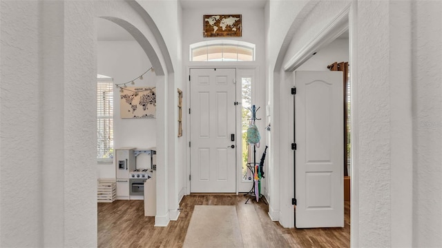 1028 15th St NE, Winter Haven, FL 33881 - foyer entrance featuring a textured wall, wood finished floors, arched walkways, and healthy amount of natural light