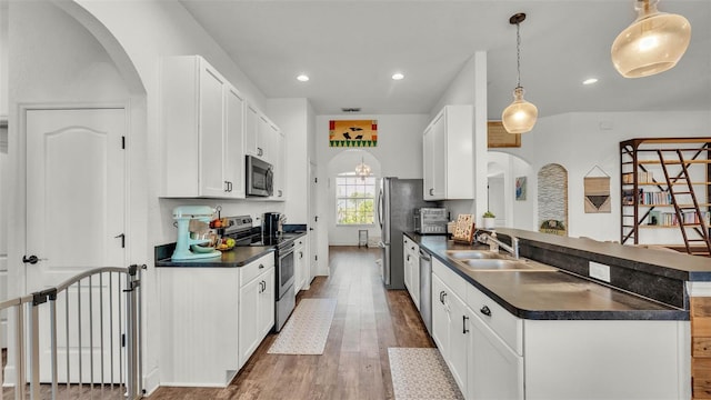 1028 15th St NE, Winter Haven, FL 33881 - kitchen featuring stainless steel appliances, dark countertops, arched walkways, hardwood / wood-style floors, and recessed lighting