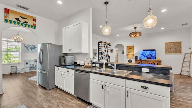 1028 15th St NE, Winter Haven, FL 33881 - kitchen with appliances with stainless steel finishes, dark countertops, a peninsula, arched walkways, and recessed lighting