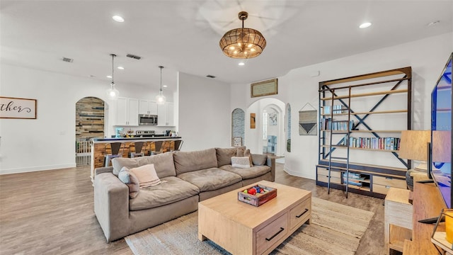 1028 15th St NE, Winter Haven, FL 33881 - living room with arched walkways, light wood-style floors, recessed lighting, and a chandelier