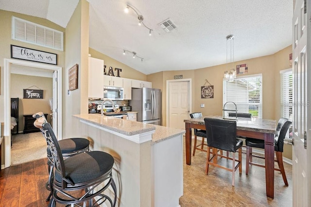 1420 Meadows Pond Dr, Bartow, FL 33830 - kitchen featuring appliances with stainless steel finishes, wood finished floors, a breakfast bar area, vaulted ceiling, and white cabinetry