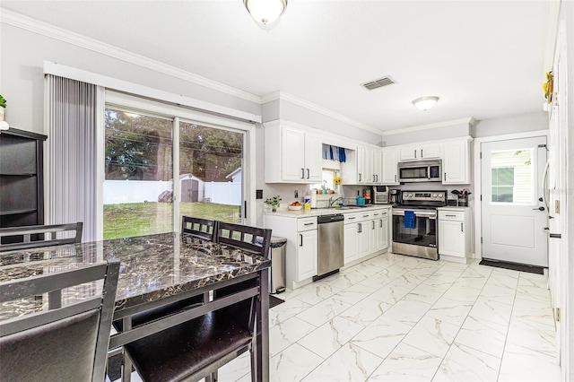 2443 Delrose Dr E, Lakeland, FL 33805 - kitchen with stainless steel appliances, light marble finish floors, white cabinetry, ornamental molding, and light countertops