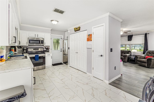 2443 Delrose Dr E, Lakeland, FL 33805 - kitchen featuring appliances with stainless steel finishes, light countertops, open floor plan, light marble finish flooring, and ornamental molding