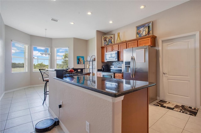 5370 Knights Station Rd, Lakeland, FL 33810 - kitchen featuring appliances with stainless steel finishes, brown cabinetry, light tile patterned floors, a kitchen island, and recessed lighting