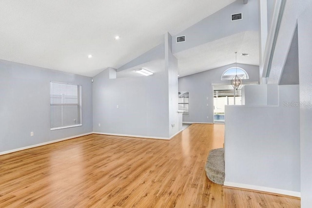 8818 Tottenham Way, Kissimmee, FL 34747 - unfurnished living room with vaulted ceiling, healthy amount of natural light, a chandelier, and light wood-style flooring