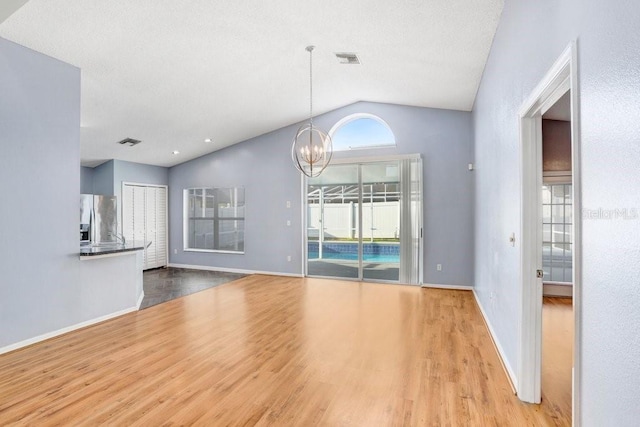 8818 Tottenham Way, Kissimmee, FL 34747 - unfurnished living room with vaulted ceiling, wood finished floors, and a chandelier