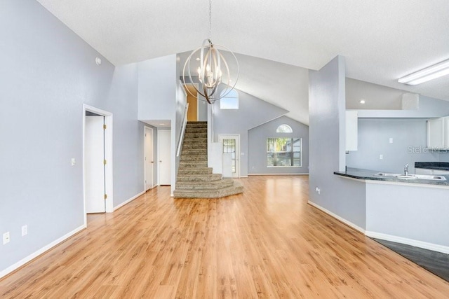 8818 Tottenham Way, Kissimmee, FL 34747 - unfurnished living room featuring light wood-type flooring, a chandelier, stairway, and high vaulted ceiling