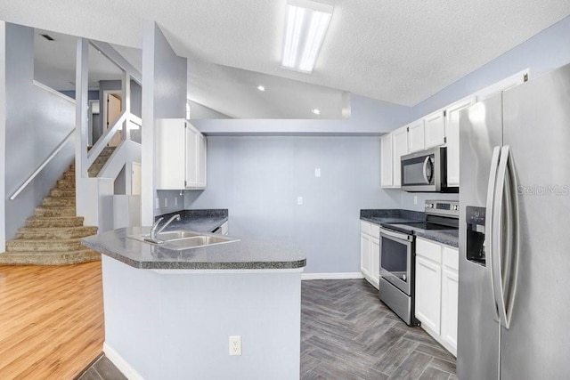 8818 Tottenham Way, Kissimmee, FL 34747 - kitchen featuring appliances with stainless steel finishes, a textured ceiling, dark countertops, a peninsula, and white cabinetry