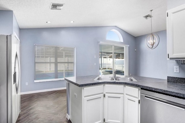 8818 Tottenham Way, Kissimmee, FL 34747 - kitchen with stainless steel appliances, lofted ceiling, a peninsula, dark countertops, and white cabinets
