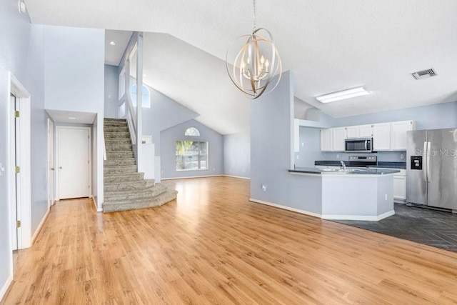 8818 Tottenham Way, Kissimmee, FL 34747 - kitchen featuring appliances with stainless steel finishes, open floor plan, light wood finished floors, a chandelier, and white cabinets