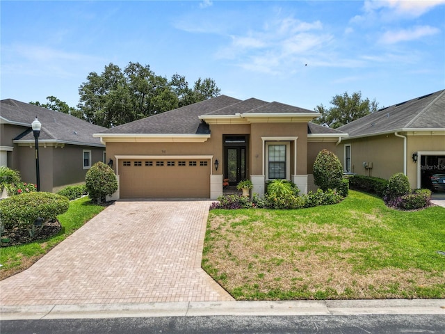 961 Christina Chase Dr, Lakeland, FL 33813 - view of front of house with decorative driveway, stucco siding, an attached garage, a front lawn, and roof with shingles