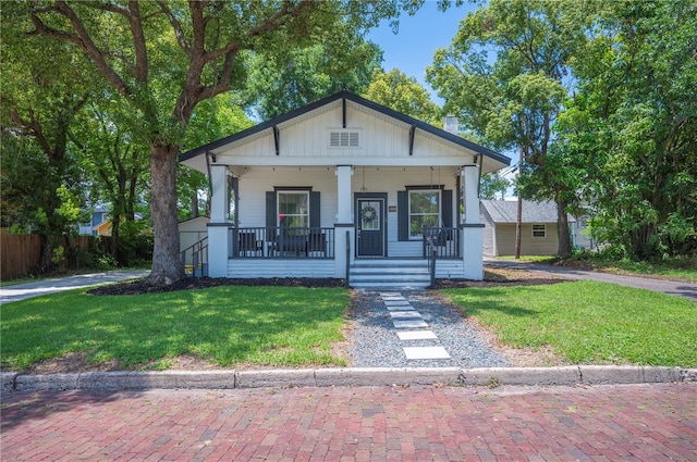 213 Cannon St, Lakeland, FL 33803 - bungalow with covered porch, a front lawn, and a chimney