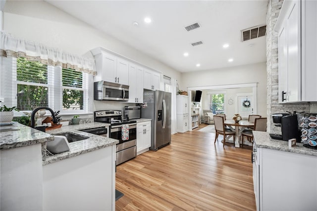 213 Cannon St, Lakeland, FL 33803 - kitchen featuring appliances with stainless steel finishes, white cabinets, light wood-type flooring, recessed lighting, and light stone counters