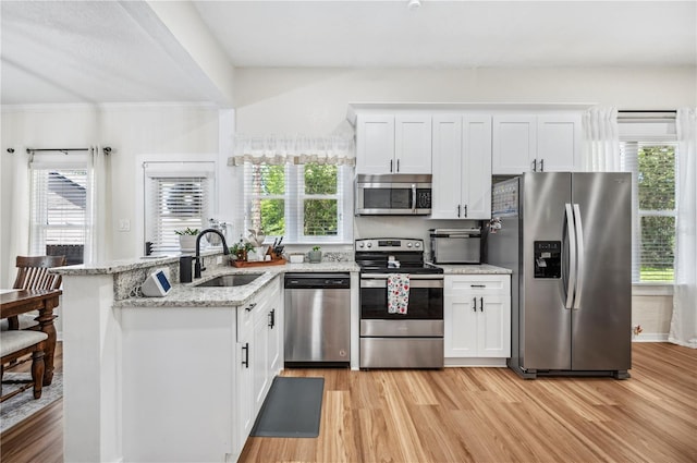 213 Cannon St, Lakeland, FL 33803 - kitchen with appliances with stainless steel finishes, light wood-style floors, white cabinets, healthy amount of natural light, and ornamental molding